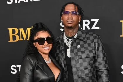 Ari Fletcher and Moneybagg Yo embracing by waterfront scenery